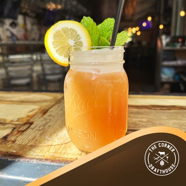 A mason jar cocktail with lemon and mint on a wooden bar at The Corner Drafthouse.